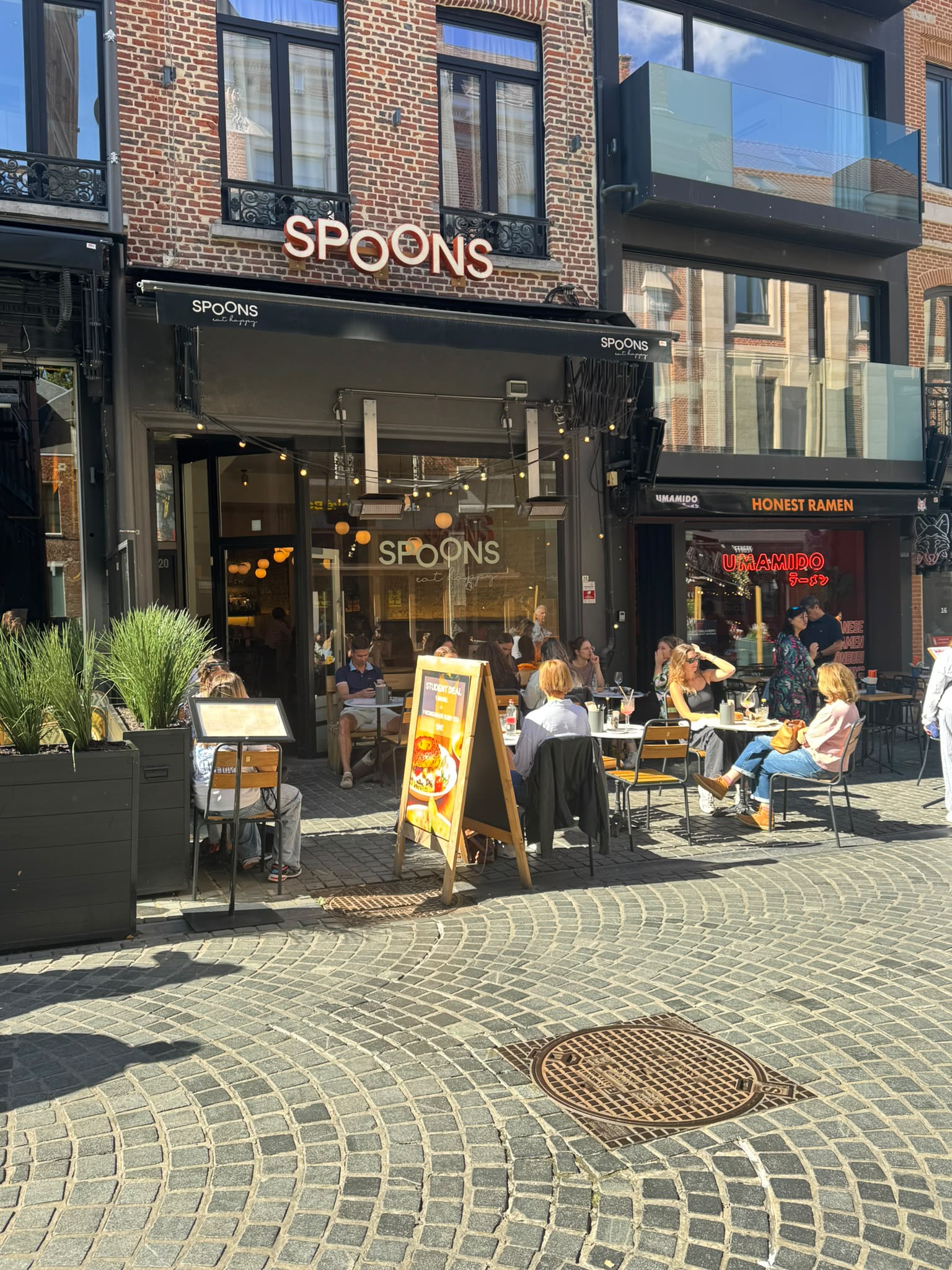 De gevel en het zonnige terras van Spoons in de Tiensestraat in Leuven