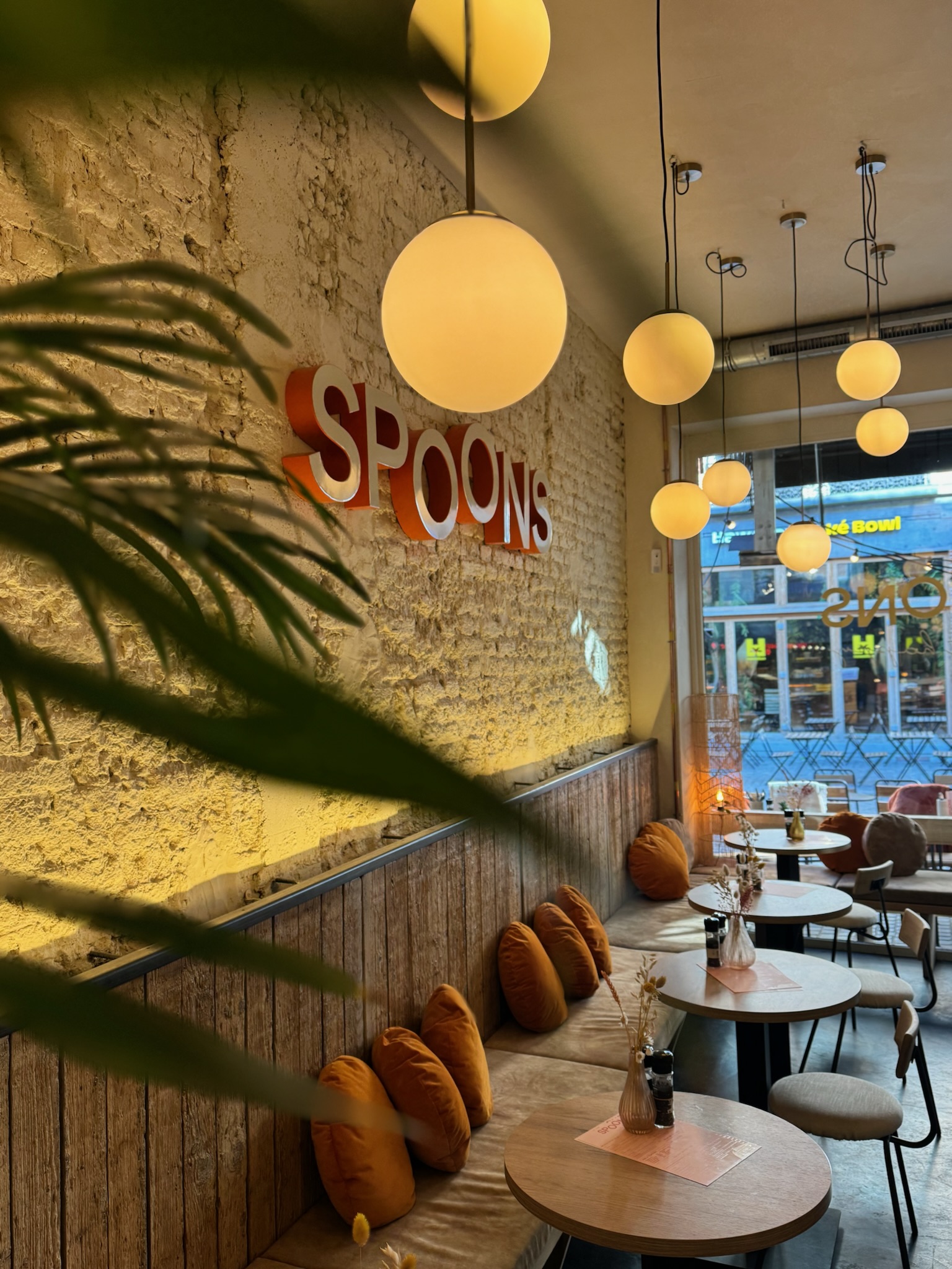 Het warme interieur van Spoons met gezellige zitplekken, planten en hanglampen