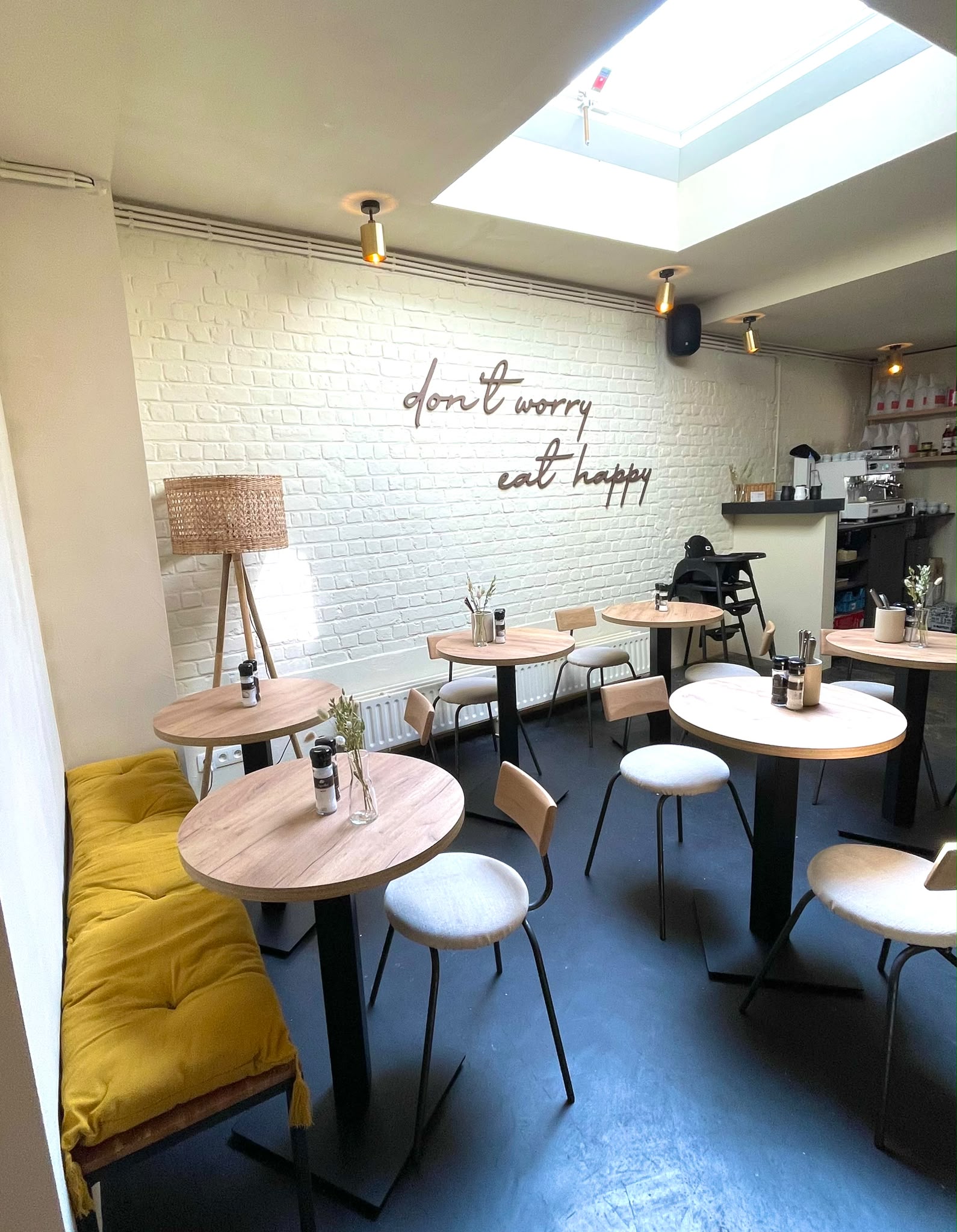 Zithoek bij Spoons in daglicht, met houten tafeltjes en de eat happy muur